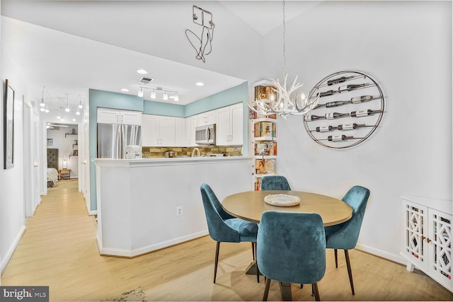 dining room featuring light wood-type flooring, a chandelier, and baseboards