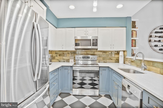kitchen with appliances with stainless steel finishes, a sink, light flooring, light countertops, and white cabinets