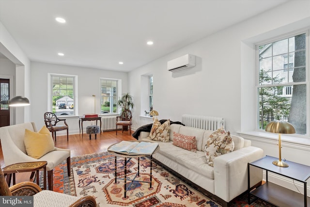 living area featuring radiator, a wall mounted AC, wood finished floors, and recessed lighting