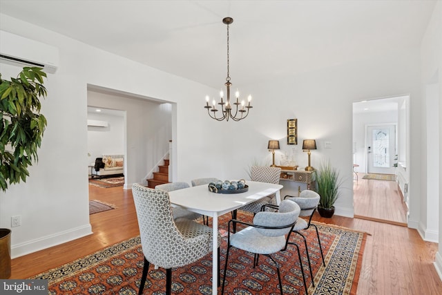 dining area with stairway, a chandelier, light wood-type flooring, and a wall mounted AC