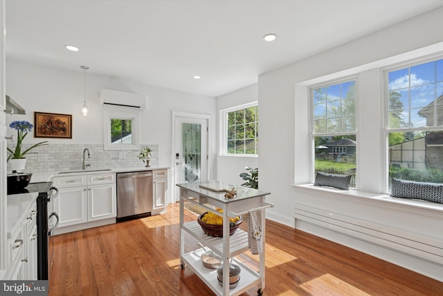 kitchen with stainless steel appliances, a sink, a wall mounted air conditioner, light wood finished floors, and recessed lighting