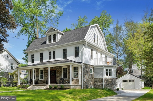 view of front of house with an outbuilding, stone siding, a balcony, covered porch, and a front lawn