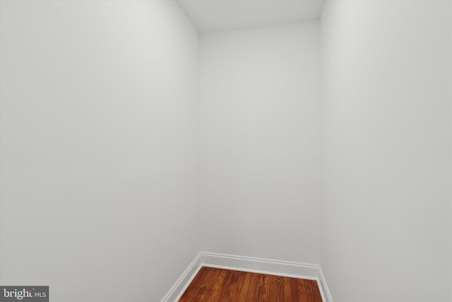 empty room featuring baseboards and dark wood finished floors