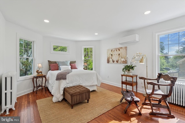bedroom featuring radiator, an AC wall unit, multiple windows, and recessed lighting