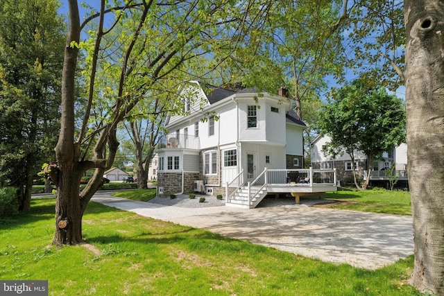 back of property with a yard, a deck, and a chimney