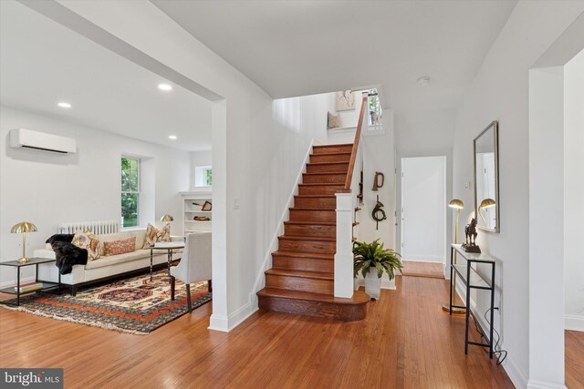 stairs with wood finished floors, an AC wall unit, radiator heating unit, baseboards, and recessed lighting