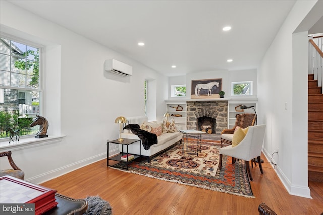 living room featuring stairs, wood finished floors, baseboards, recessed lighting, and a fireplace