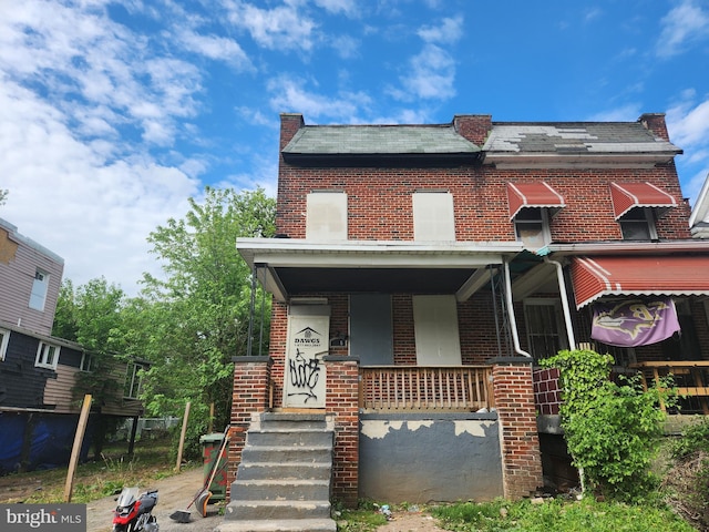 view of front of house featuring brick siding and a porch