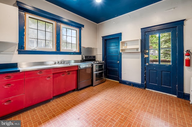 kitchen with stainless steel counters, dishwasher, double oven range, red cabinetry, and a sink