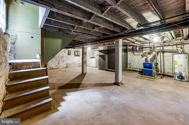 unfinished basement featuring gas water heater, stairway, a heating unit, and washing machine and dryer