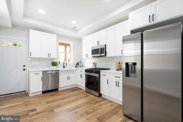 2312 Edmondson Ave, Baltimore, MD 21223 - kitchen with appliances with stainless steel finishes, a tray ceiling, white cabinets, light countertops, and light wood-type flooring