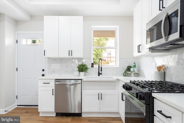 2312 Edmondson Ave, Baltimore, MD 21223 - kitchen featuring stainless steel appliances, white cabinetry, light wood-style floors, light countertops, and a sink