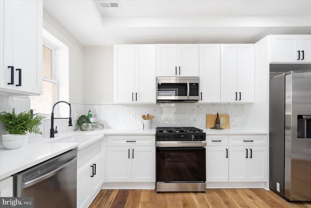 2312 Edmondson Ave, Baltimore, MD 21223 - kitchen featuring appliances with stainless steel finishes, a sink, white cabinetry, light countertops, and light wood-type flooring
