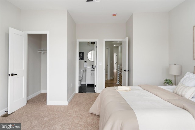 2312 Edmondson Ave, Baltimore, MD 21223 - bedroom featuring a walk in closet, light colored carpet, baseboards, a closet, and connected bathroom