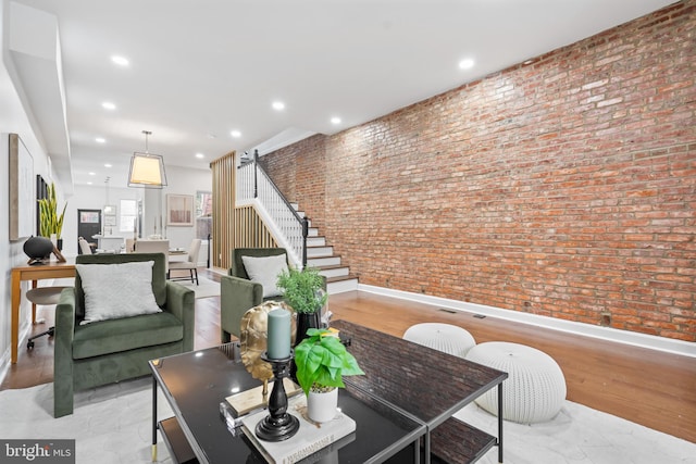 living area featuring recessed lighting, brick wall, baseboards, and stairs