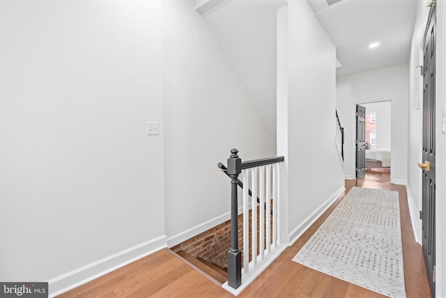 corridor with wood finished floors, an upstairs landing, baseboards, and recessed lighting