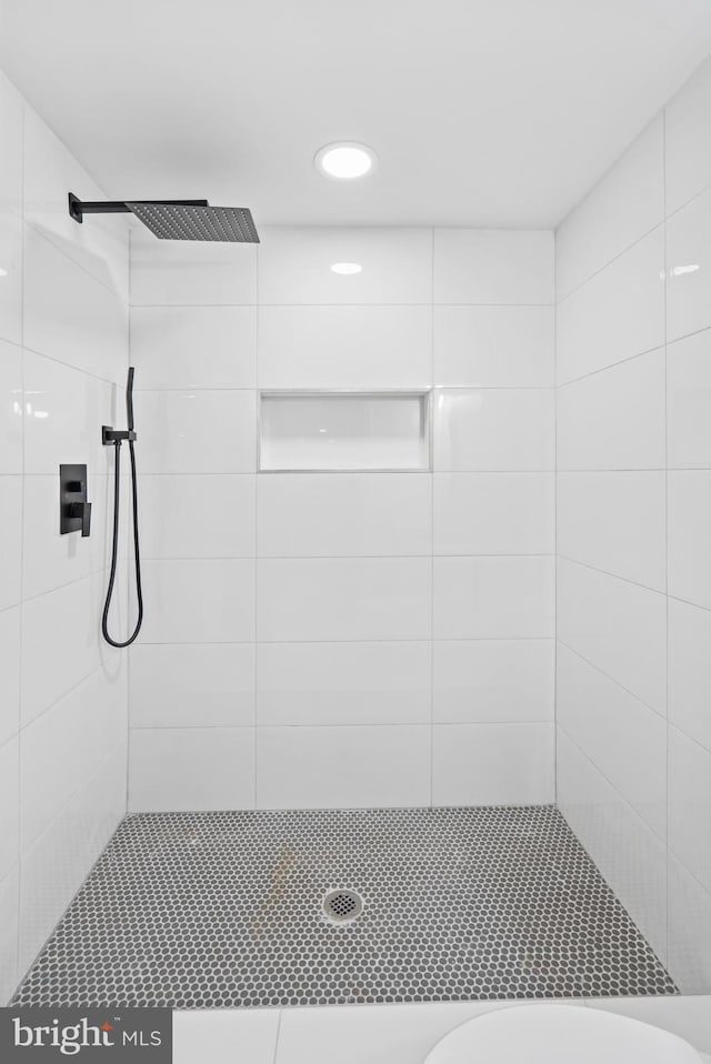 bathroom with toilet, tiled shower, and recessed lighting