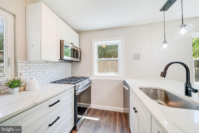 kitchen featuring stainless steel appliances, a sink, dark wood finished floors, tasteful backsplash, and white cabinets