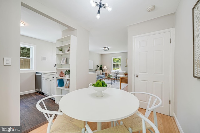 dining space with light wood-type flooring, a chandelier, and baseboards