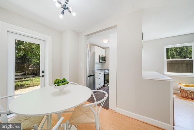 dining area with light wood-style flooring, a chandelier, and baseboards