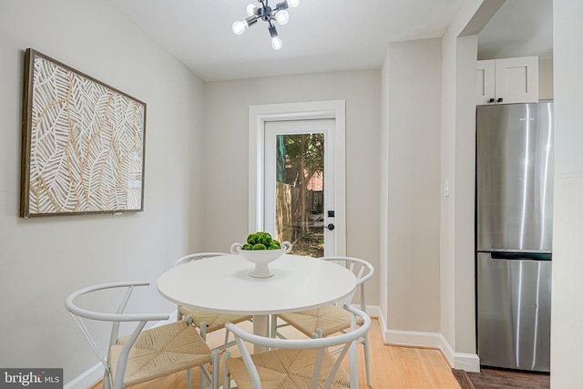dining space featuring baseboards, wood finished floors, and a chandelier