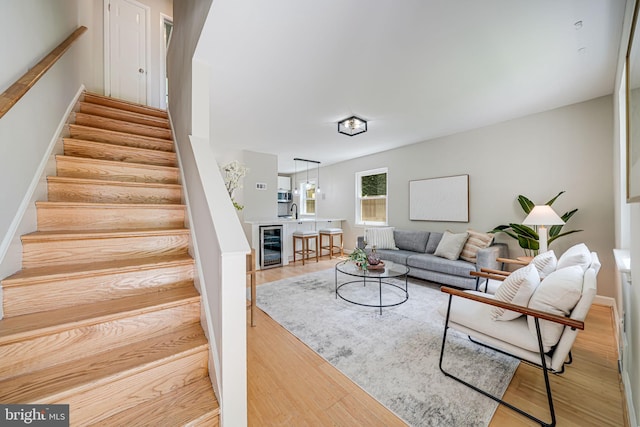 living area with beverage cooler, stairs, and wood finished floors