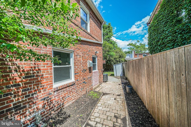 view of property exterior featuring brick siding and fence