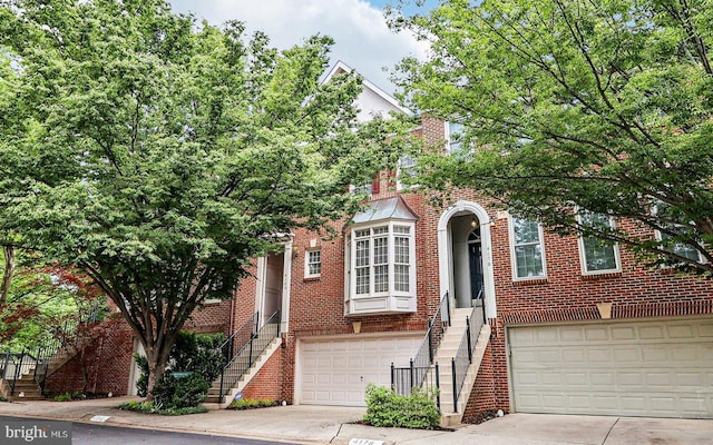 view of front facade featuring stairs, an attached garage, driveway, and brick siding
