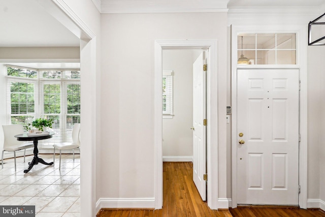 foyer with baseboards, light wood-type flooring, and crown molding