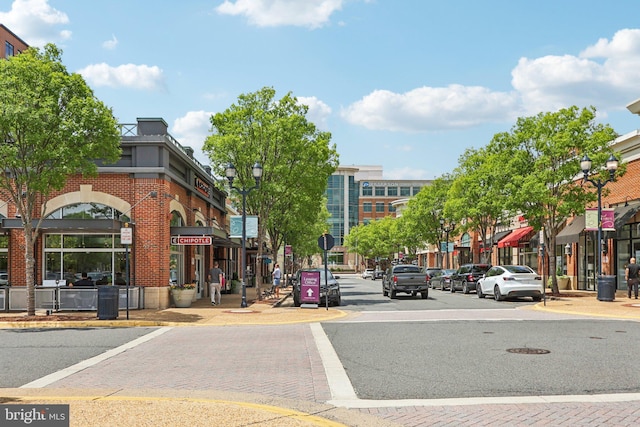 view of asphalt road featuring street lights, sidewalks, curbs, and traffic signs