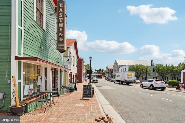 view of asphalt street featuring street lights, curbs, sidewalks, and a residential view