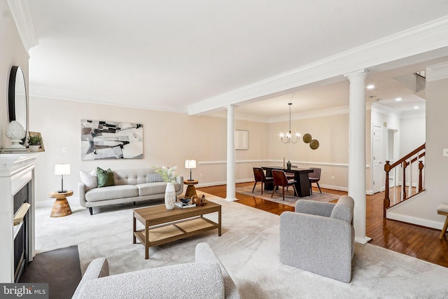 living area with decorative columns, a fireplace, wood finished floors, ornamental molding, and stairway