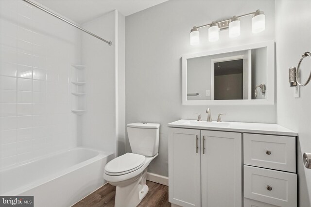 bathroom with wood finished floors, toilet, vanity, baseboards, and bathing tub / shower combination
