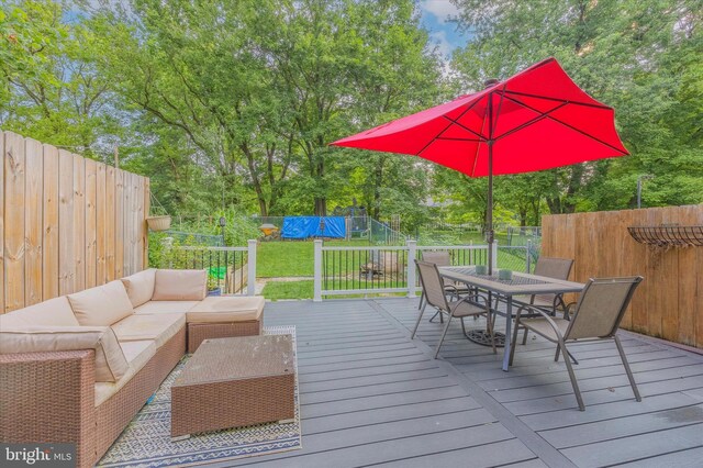 deck with outdoor dining area, an outdoor hangout area, and view of wooded area