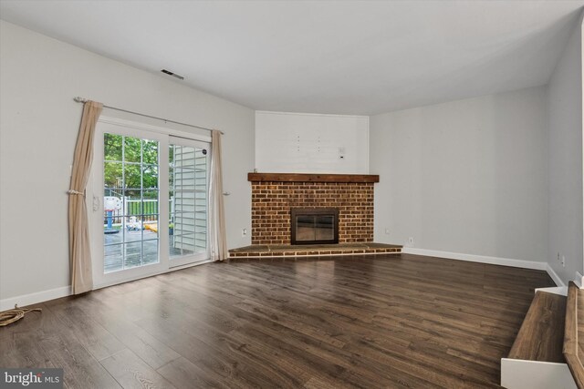 unfurnished living room featuring dark wood-type flooring, baseboards, and a fireplace
