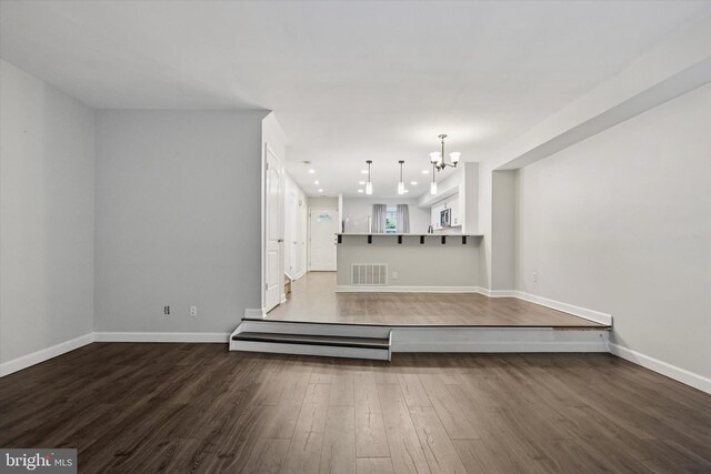unfurnished living room with a chandelier, wood finished floors, baseboards, and recessed lighting