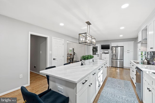 15807 Marlington Dr, Dumfries, VA 22025 - kitchen with stainless steel appliances, light wood finished floors, a kitchen bar, a center island, and white cabinets
