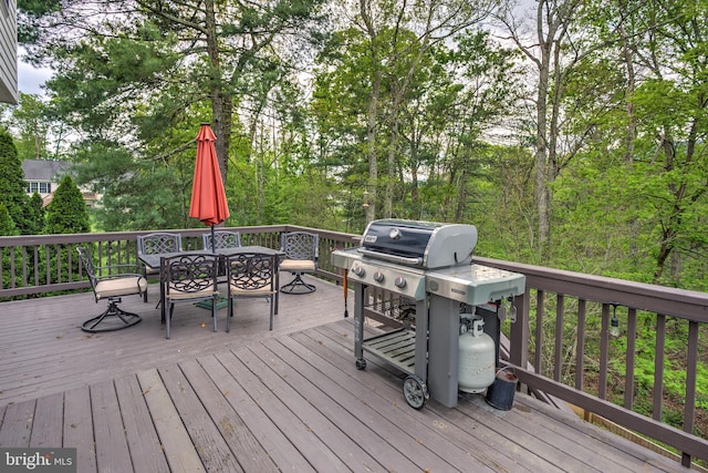 wooden terrace featuring outdoor dining space and grilling area