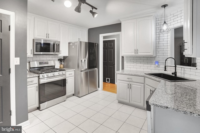 kitchen with backsplash, white cabinetry, appliances with stainless steel finishes, and a sink