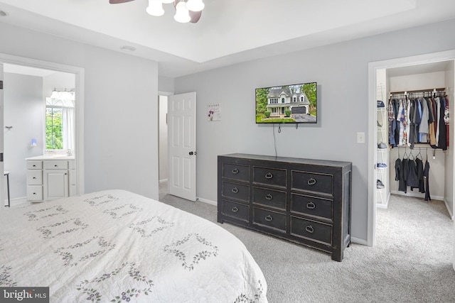 bedroom featuring a walk in closet, light colored carpet, a closet, and baseboards