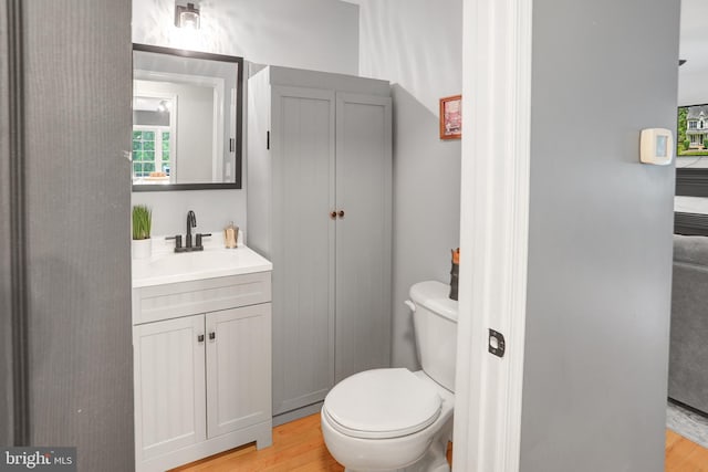 half bathroom featuring toilet, vanity, and wood finished floors
