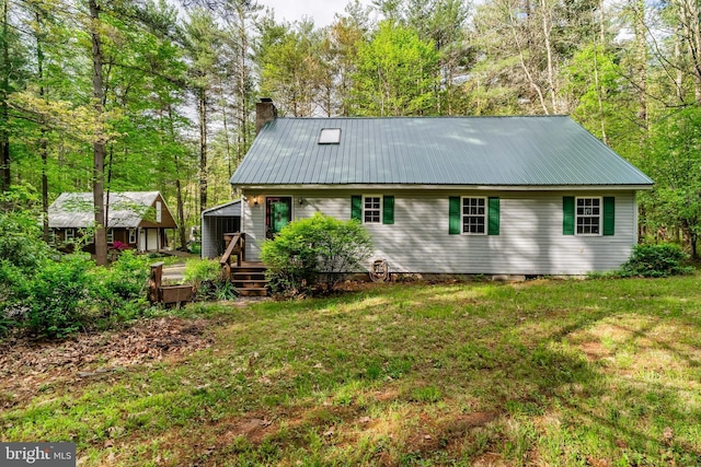 back of property featuring metal roof, a chimney, a wooden deck, and a lawn