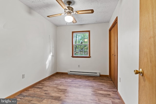 empty room with a baseboard radiator, wood finished floors, a textured ceiling, a ceiling fan, and baseboards
