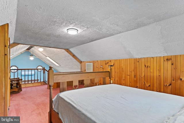 carpeted bedroom with vaulted ceiling, a textured ceiling, and wood walls