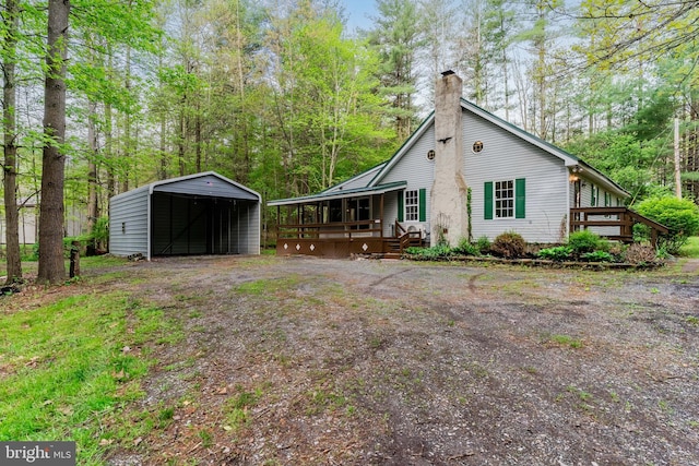 view of side of property with a detached carport, a chimney, and covered porch