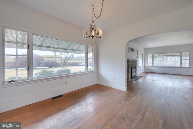 10 E Canal Rd, York, PA 17404 - unfurnished living room featuring baseboards, a tiled fireplace, wood-type flooring, visible vents, and arched walkways