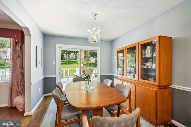 dining space featuring wood finished floors, a chandelier, and baseboards