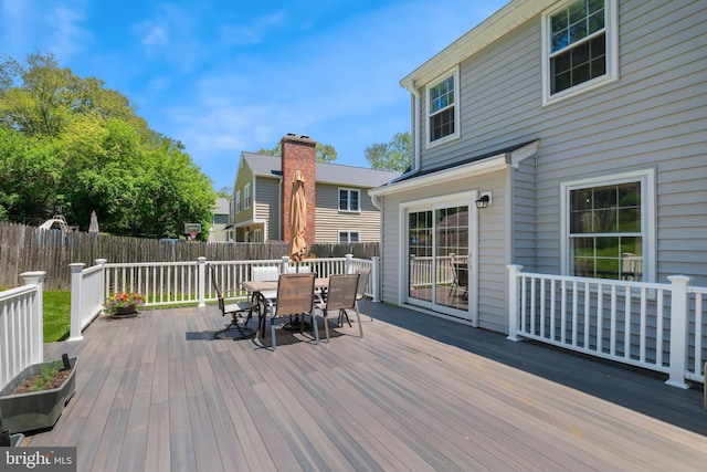 wooden terrace with outdoor dining space and a fenced backyard