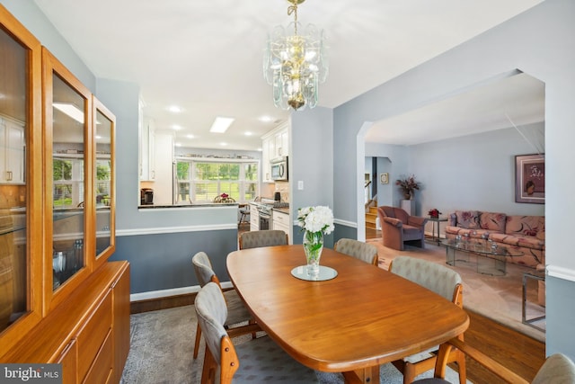 dining space featuring arched walkways, dark wood-style floors, baseboards, a chandelier, and recessed lighting