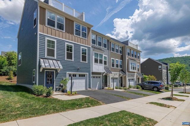 multi unit property featuring a residential view, a garage, board and batten siding, a front yard, and driveway
